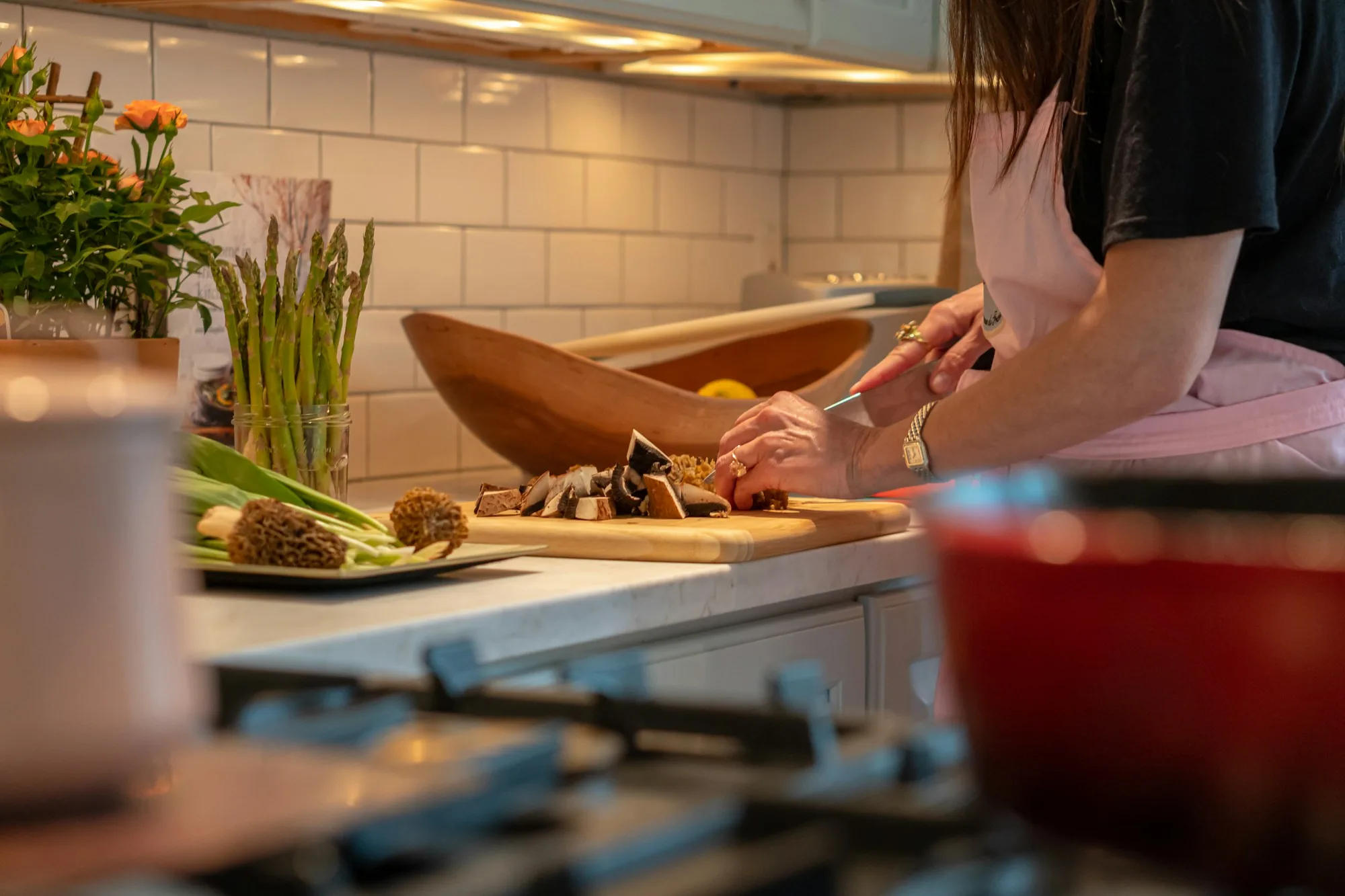 Hands carefully prepping ingredients on a wooden cutting board in a warm-lit kitchen — the disciplined execution that lives in restaurant SOPs